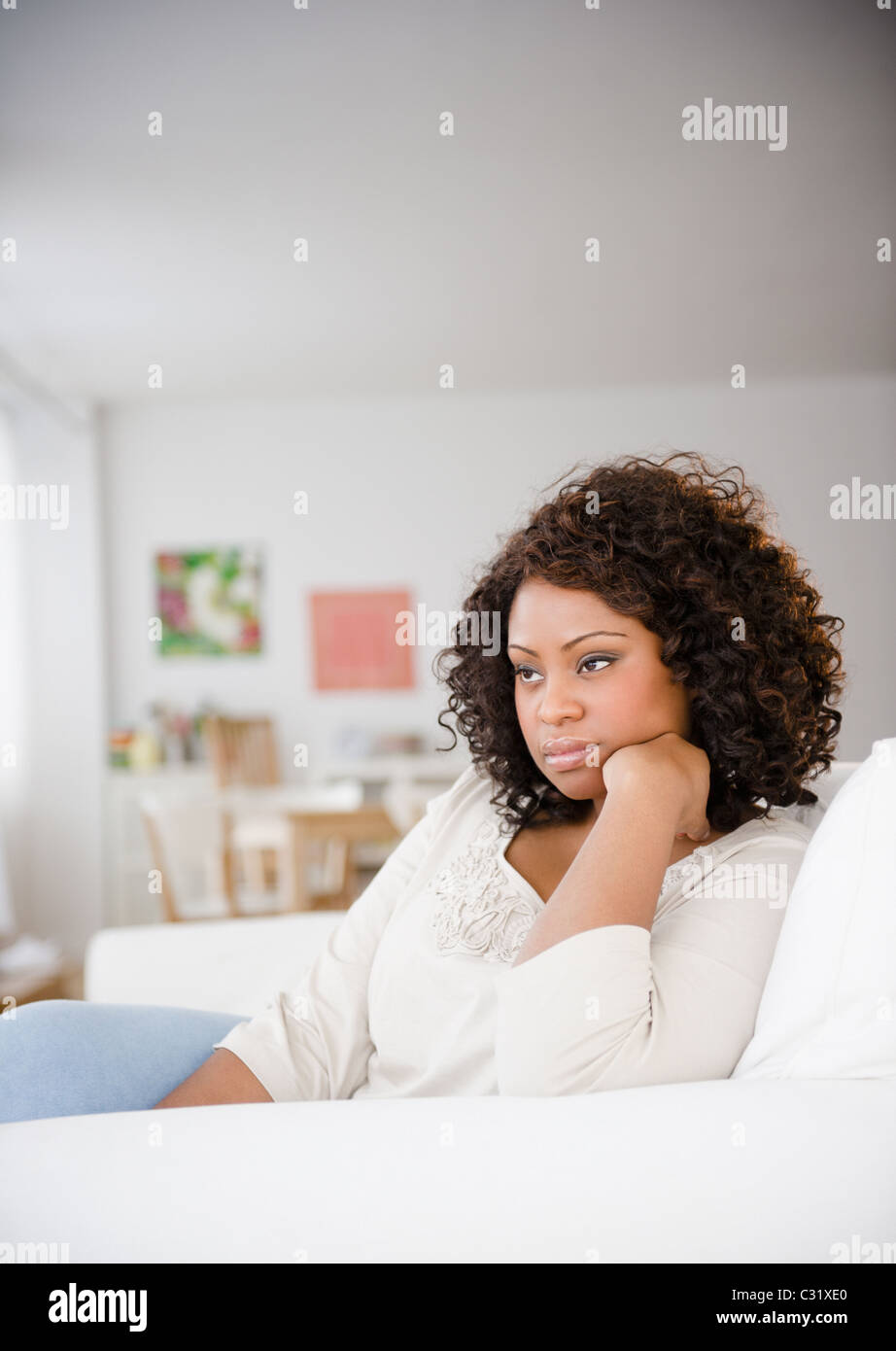 Traurige afroamerikanische Frau sitzend auf sofa Stockfoto