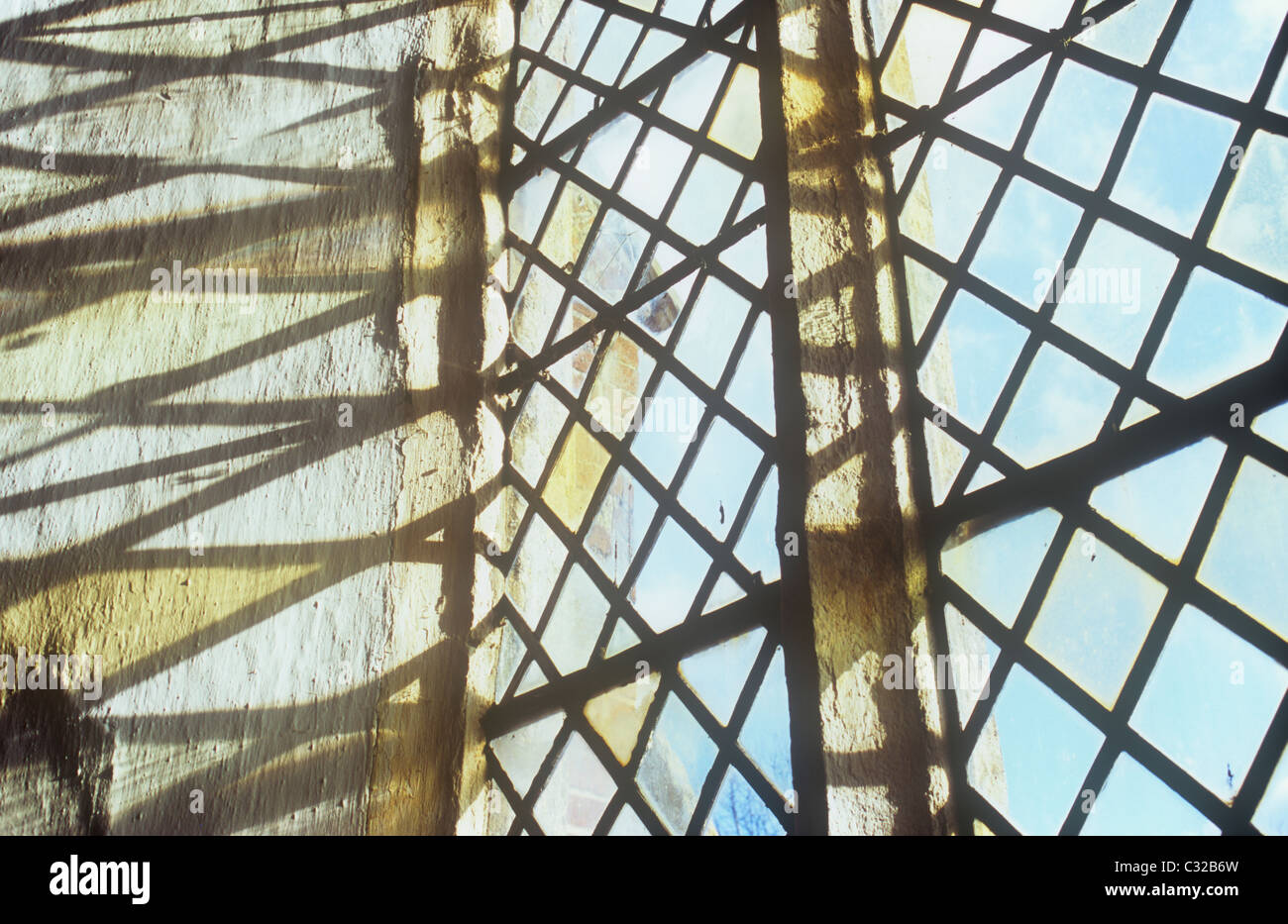 Projektion von deutlich kleiner Diamant verbleit Glasscheiben Fenster auf Seite Creme lackiert rauhe Aussparung mit blauem Himmel sichtbar Stockfoto