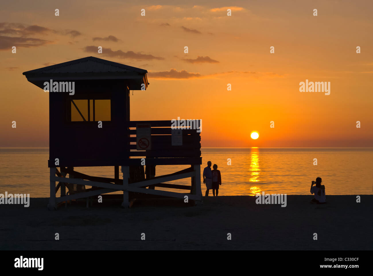 Leben Wache stehen und Menschen Silhouette gegen orange sunset Himmel über Golf von Mexiko aus Venice Beach Florida Stockfoto