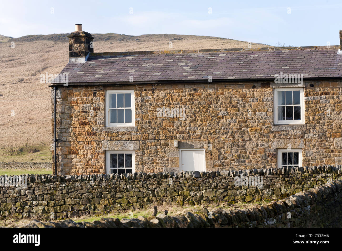 Eine Steinhütte auf einmal gebraut, Northumberland, England UK - Hadrian Wand verläuft entlang der Hügel im Hintergrund Stockfoto