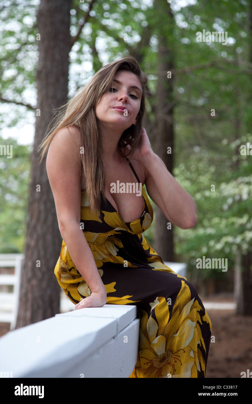 Schöne weiße Frau trägt ein gelbe-schwarze Kleid, draußen sitzen auf einem weißen Zaun Stockfoto