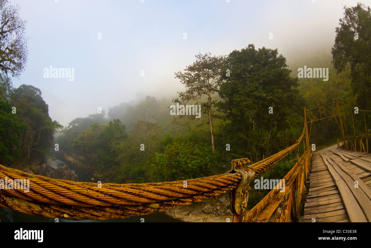 Eine alte Hängebrücke, die einen Dschungel in Guatemala Fluss Stockfoto