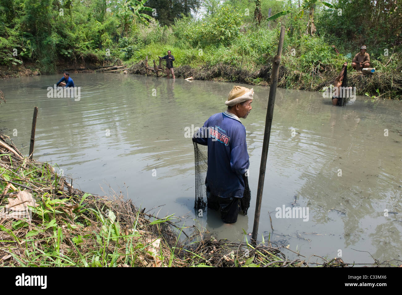 Thai Männer Angeln in einen Entwässerungskanal Deich im Isan-Nord-Ost-Thailand. Sie verwenden traditionelle gewichteten werfen Netze. Stockfoto