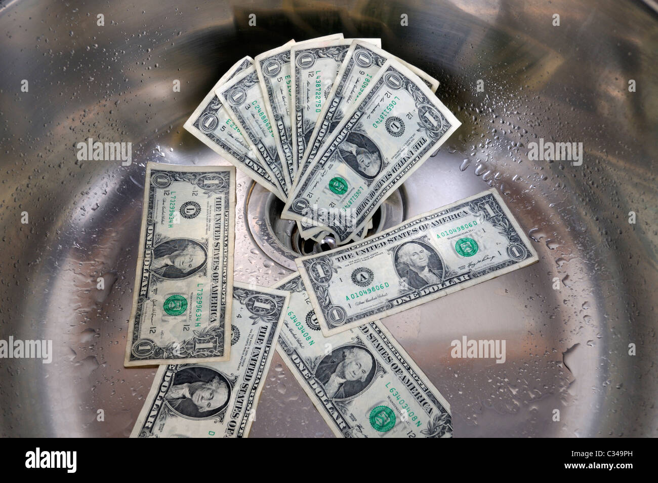 US-Dollar in ein Waschbecken Abfluss. Geld, das Konzept der Abfluss hinunter. Stockfoto