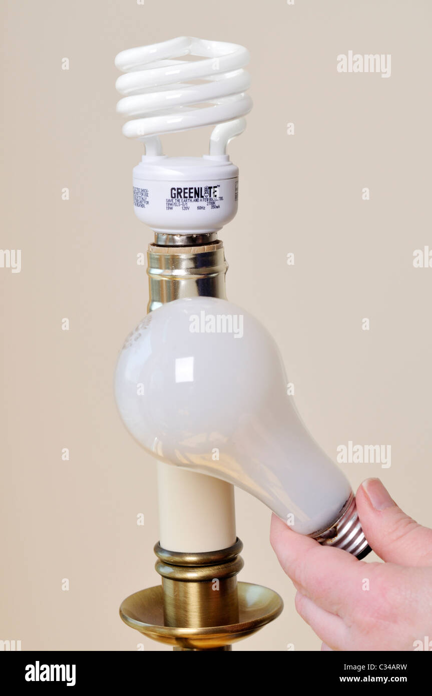 Erwachsenen Hand Lampenwechsel Licht einer Lampe aus einer Glühlampe auf eine weitere energiesparende Kompaktleuchtstofflampe. USA Stockfoto