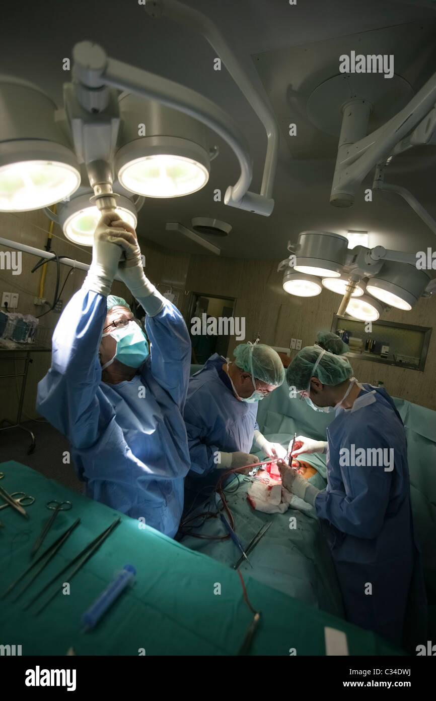 Krankenschwester passt Beleuchtung, als Ärzte im Krankenhaus-OP-Saal operieren Stockfoto