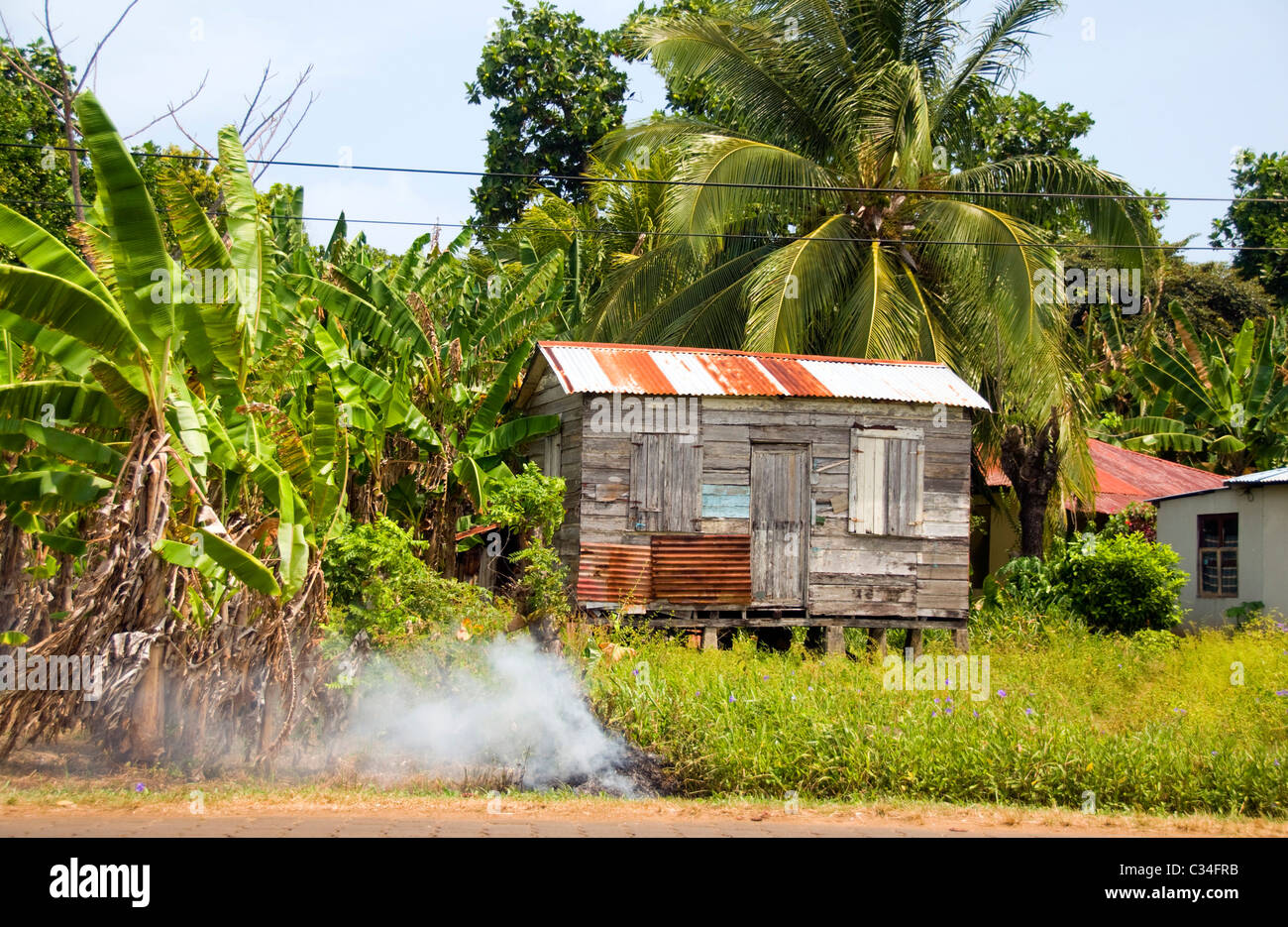 Rauchen Sie, Luftverschmutzung Müll brennende Banane Dschungel marode Schindeln Zink Baumhaus Corn Island Nicaragua Zentralamerika Stockfoto