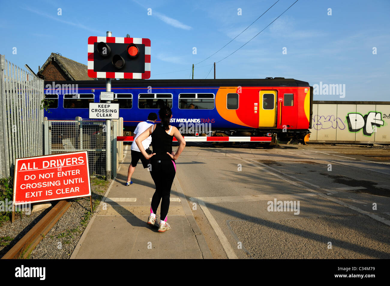 Jogger am ein Bahnübergang warten, während eine lokale s-Bahn Beeston Nottingham England uk verläuft Stockfoto