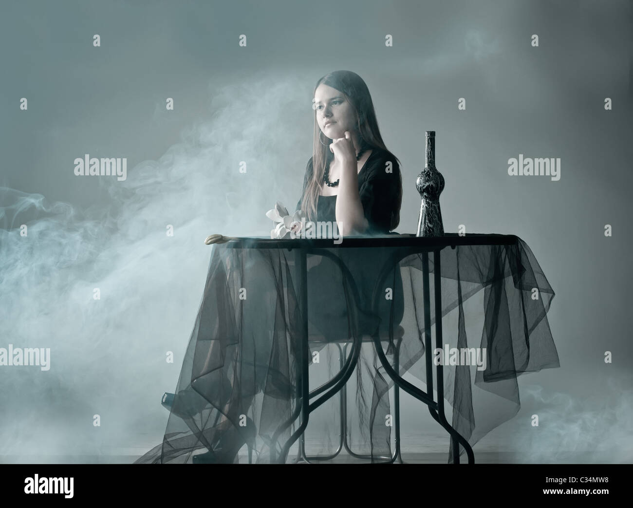 Frau sitzt hinter Tisch in Rauch Stockfoto