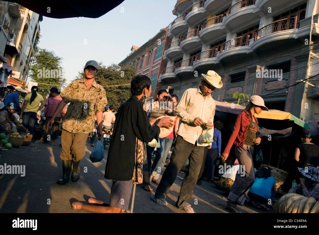 Ein asiatischer Mann spaziert vorbei an einem behinderten amputiert Mann wer um Geld in Phnom Penh, Kambodscha betteln ist. Stockfoto