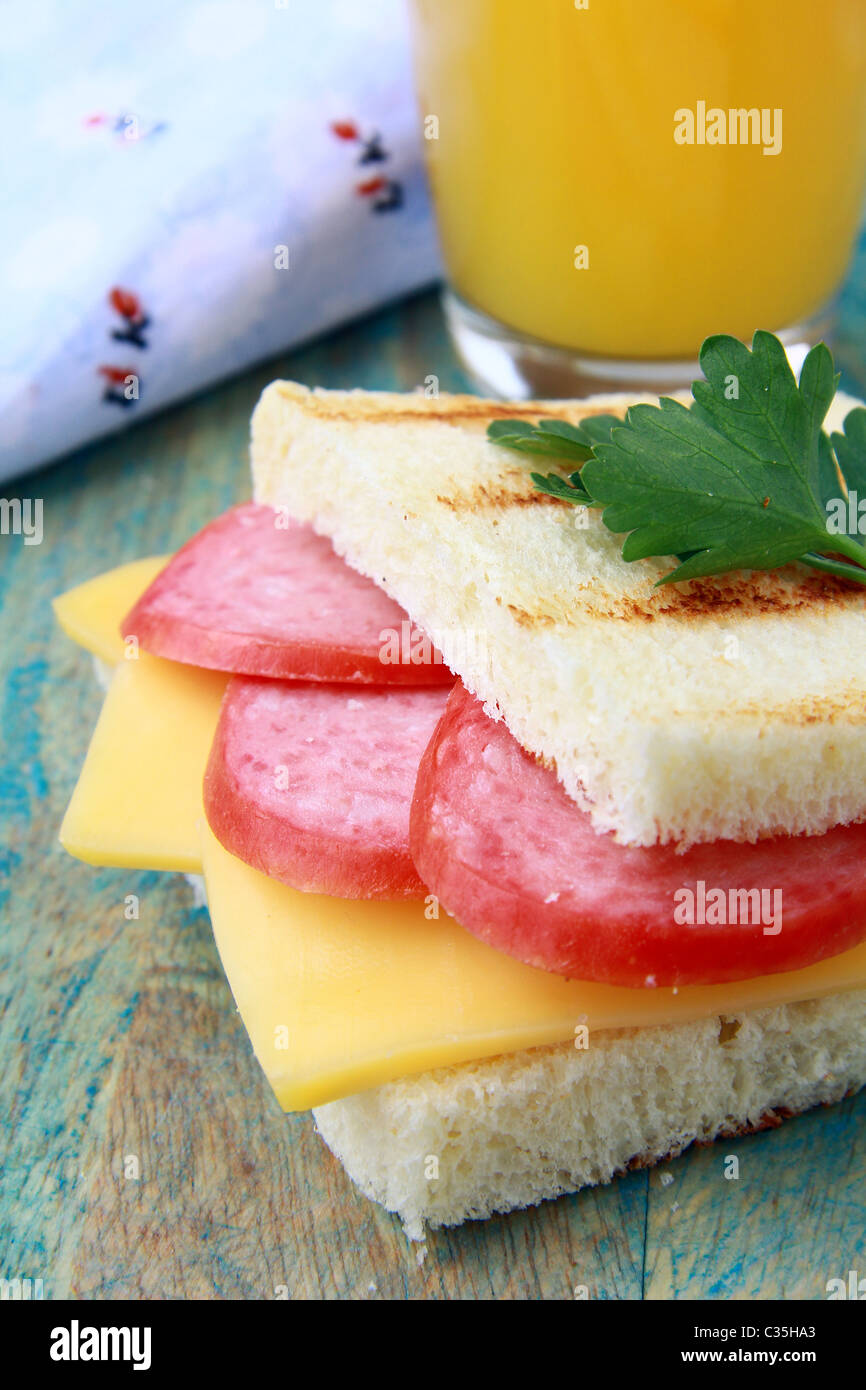 Frühstücks-Sandwich mit Käse und Salami und Saft Stockfoto