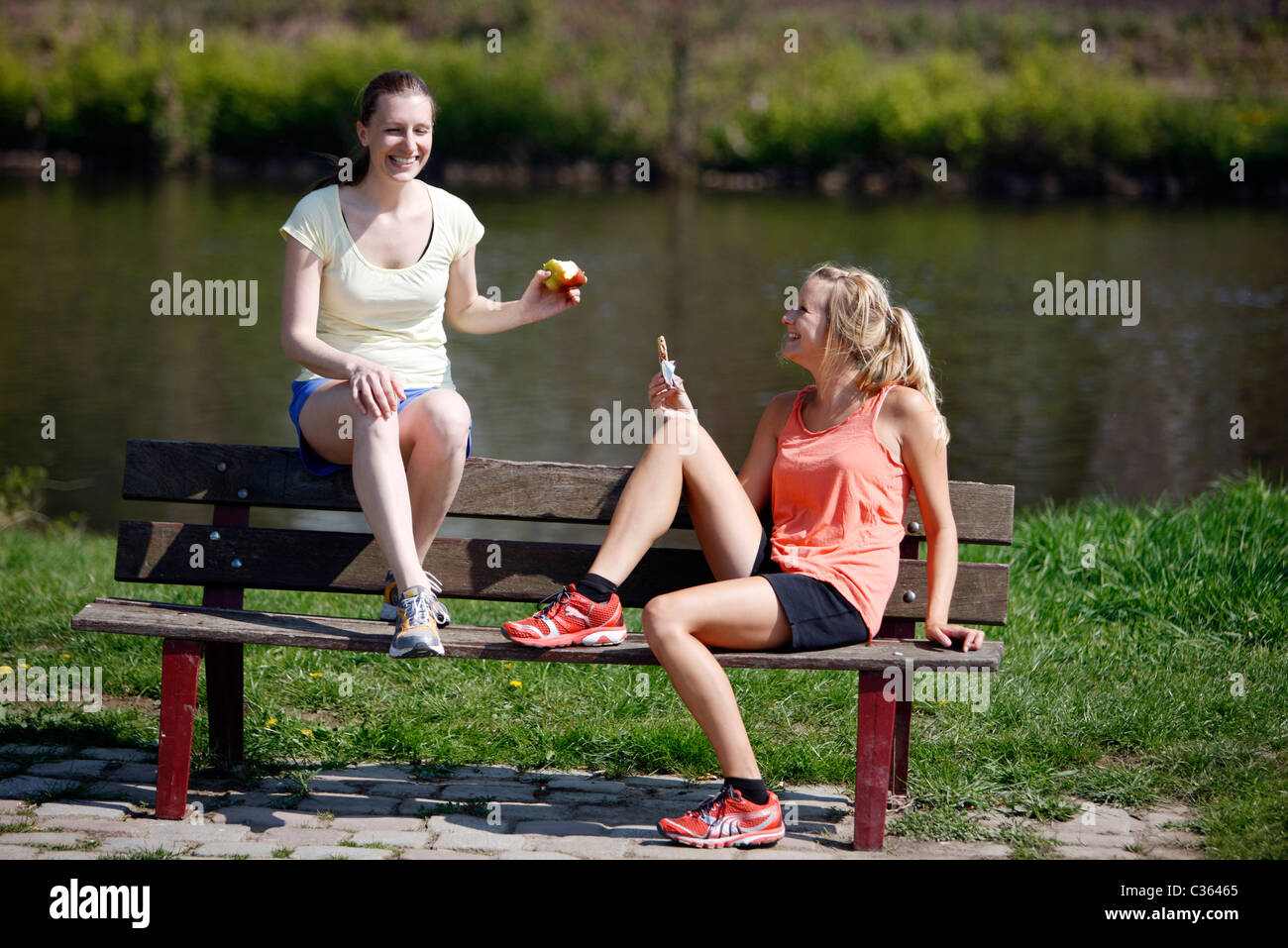 Zwei junge weibliche Hobby-Läufer entspannend nach dem Sport. Essen und trinken. Stockfoto
