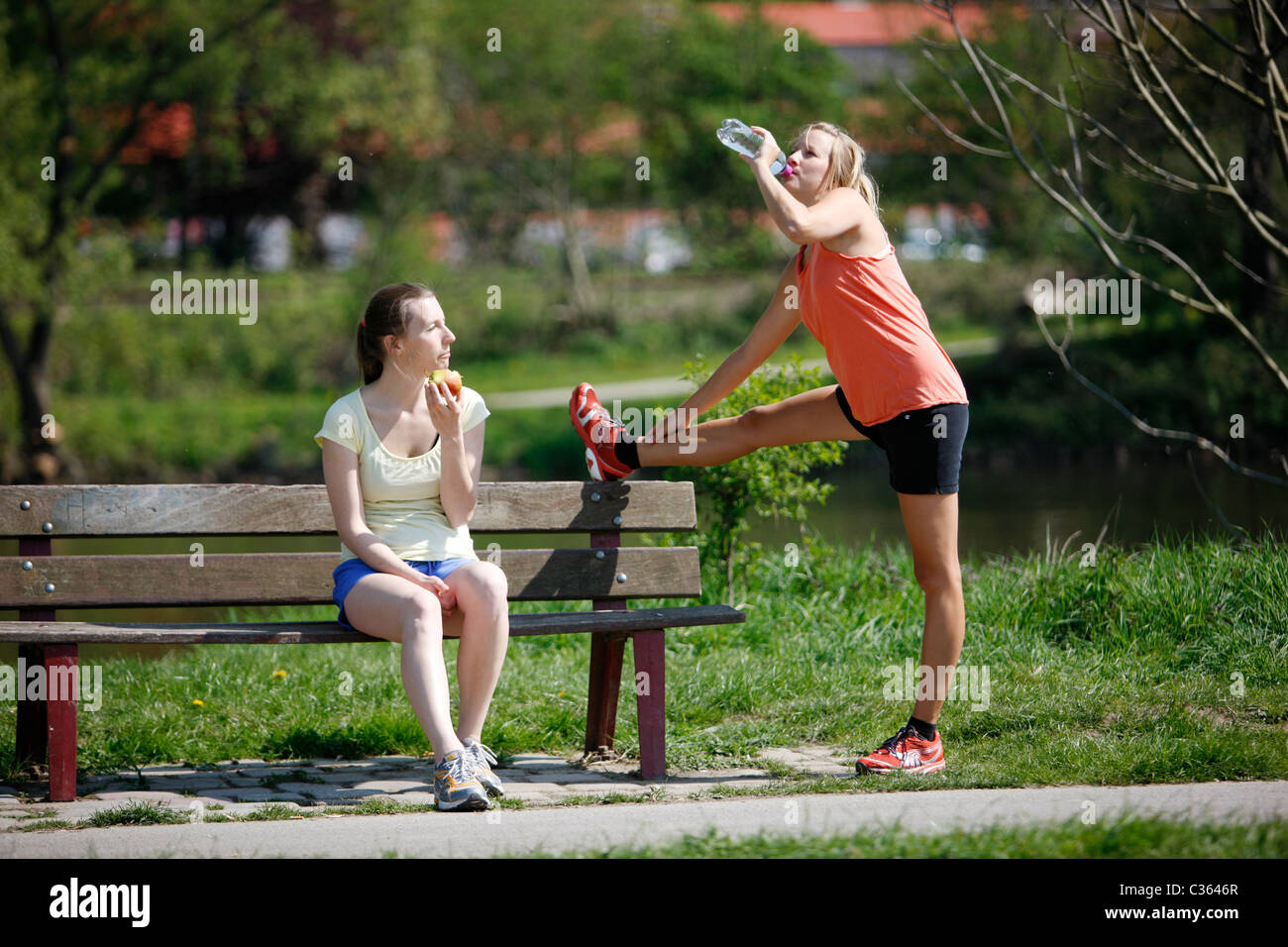 Zwei junge weibliche Hobby-Läufer entspannend nach dem Sport. Essen und trinken. Stockfoto