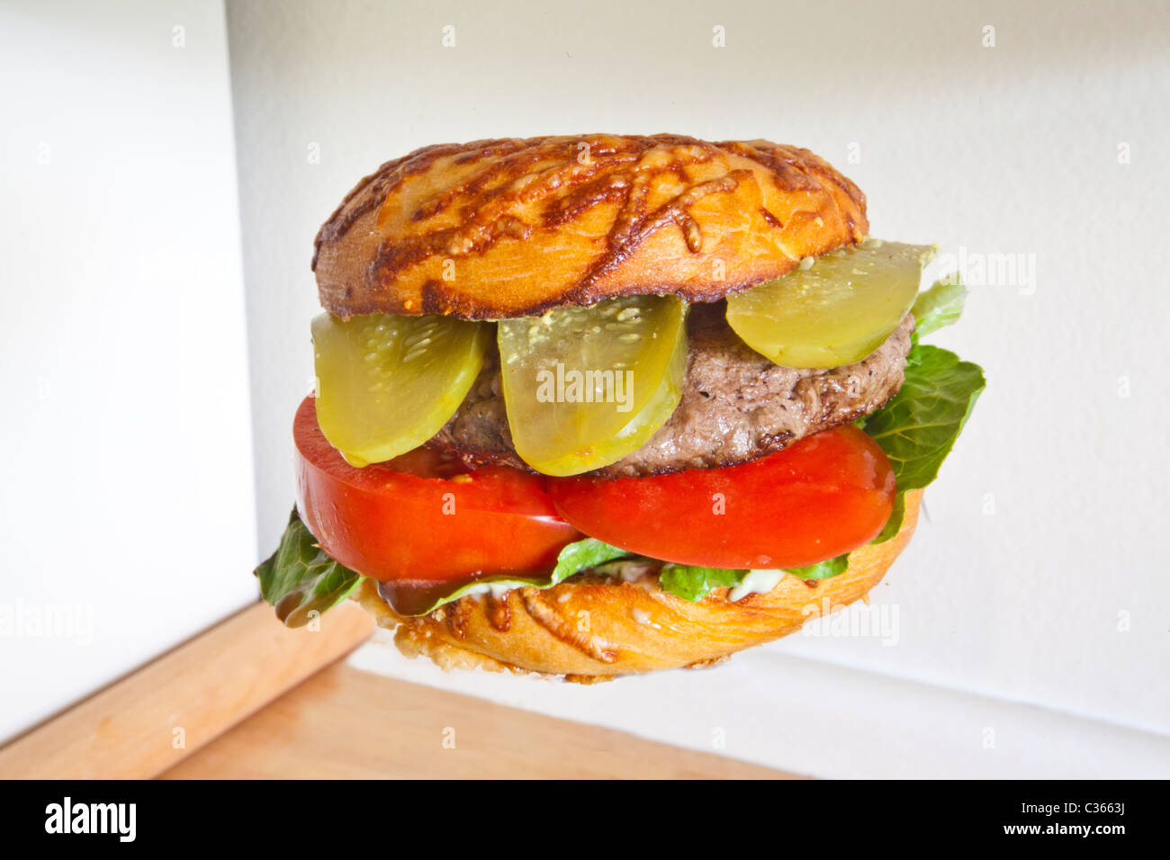 Ein Hamburger auf einem Käse-Bagel mit Salat Tomate und Gurke dill Stockfoto