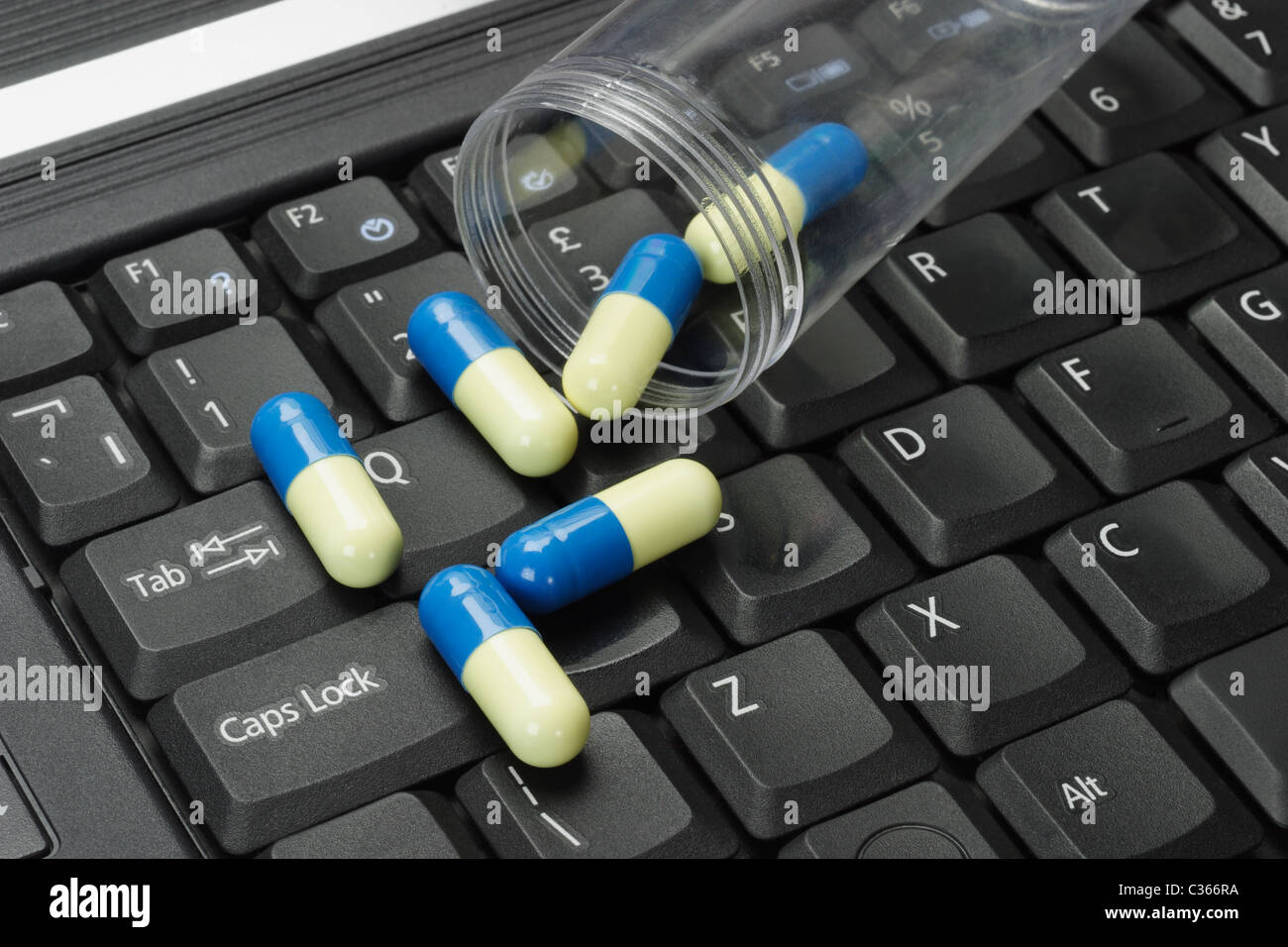 Konzeptbild von Pillen auf schwarzer Laptoptastatur verschüttet Stockfoto