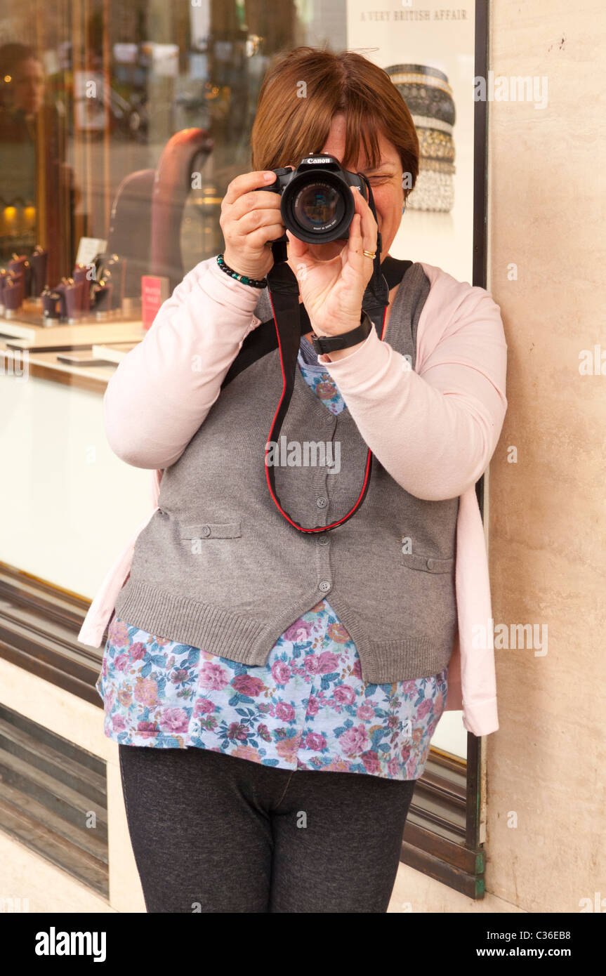 Eine Fotografin, die eine Aufnahme mit ihrer Canon digitale SLR-Kamera im Vereinigten Königreich Stockfoto