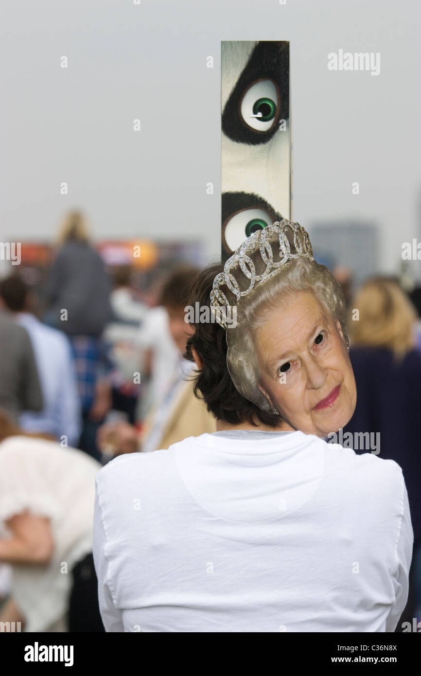 Königliche Hochzeit, Nachtschwärmer sehen riesige Bildschirme mit Periskop, während sie eine Maske der Königin Hyde Park, London, tragen Stockfoto