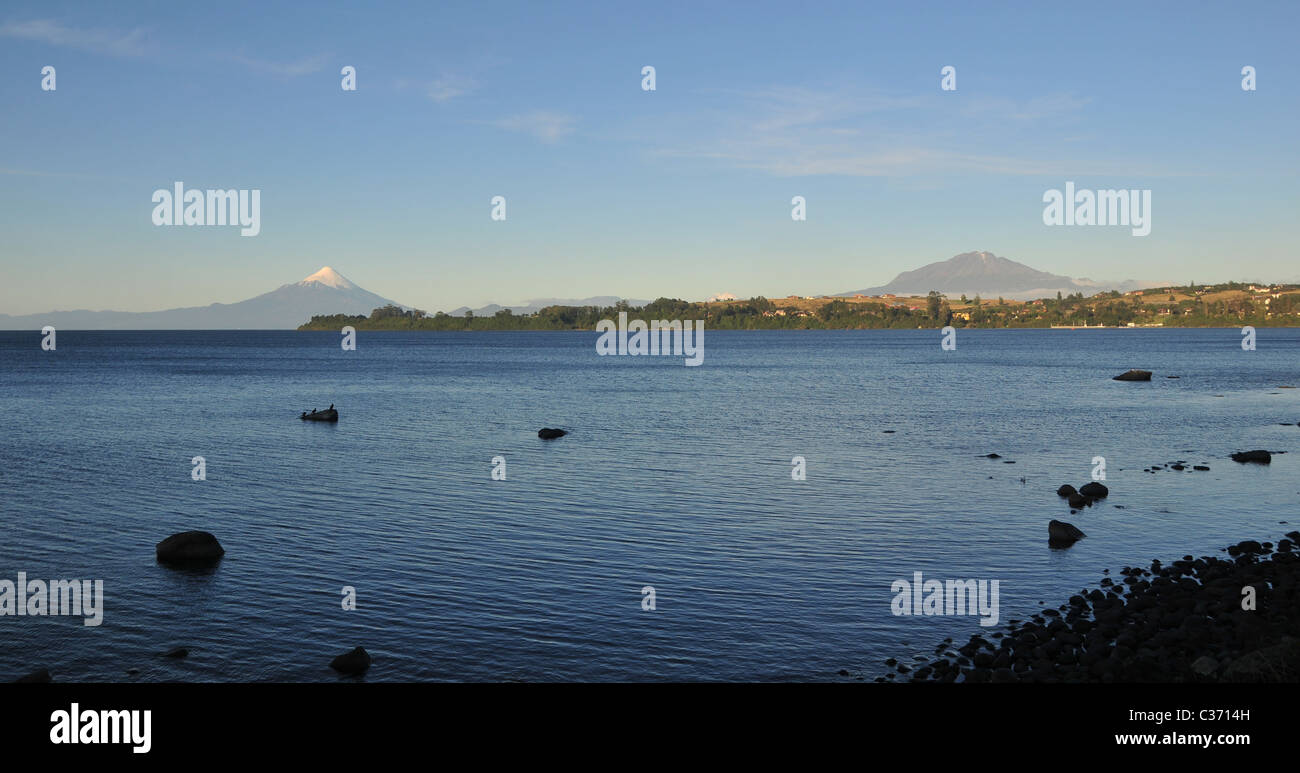 Wolkenfetzen, blauen Himmel Abend Strandblick auf See Llanquihue, Osorno und Calbuco Vulkane, Puerto Varas, Chile blickt Stockfoto