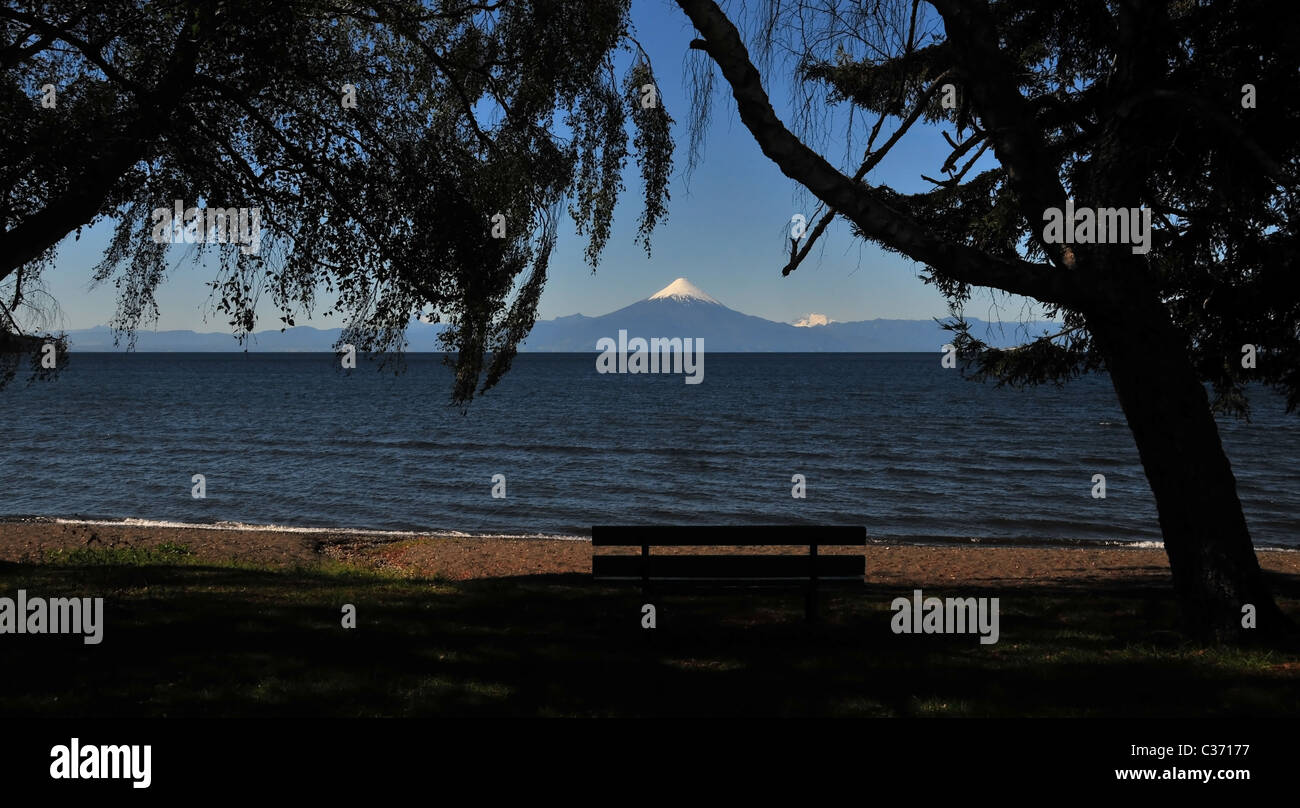 Blauer Himmel See Llanquihue Strandblick, mit Sitz und Silhouette Bäume, Volcan Osorno, von der Küste Frutillar, Chile Stockfoto