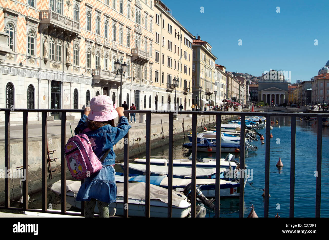 Ein einsame kleine Mädchen freut sich auf einige Boote in einem Kanal an der Adria. Stockfoto