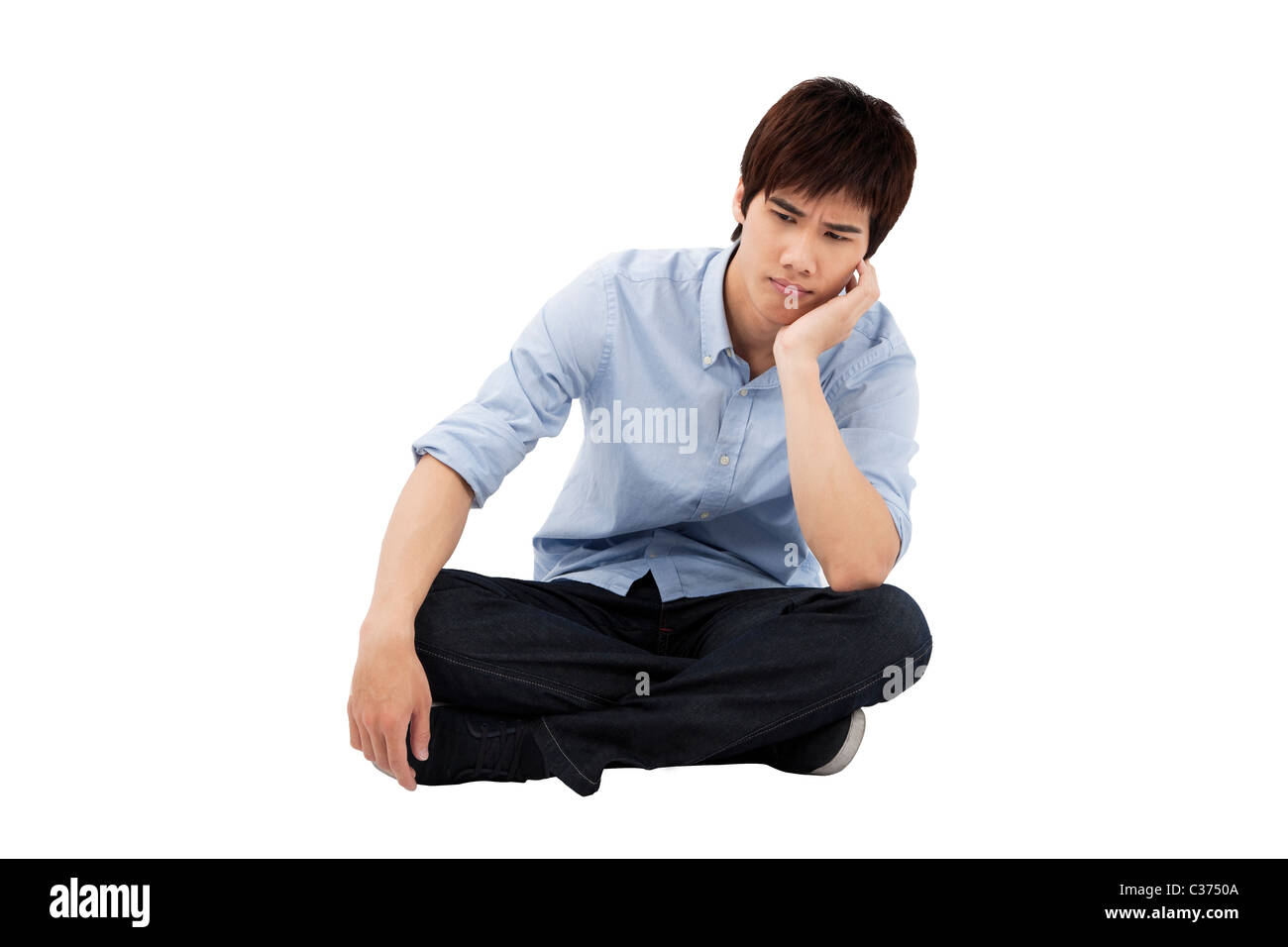 jungen Mann auf dem Boden sitzend verärgert Stockfoto