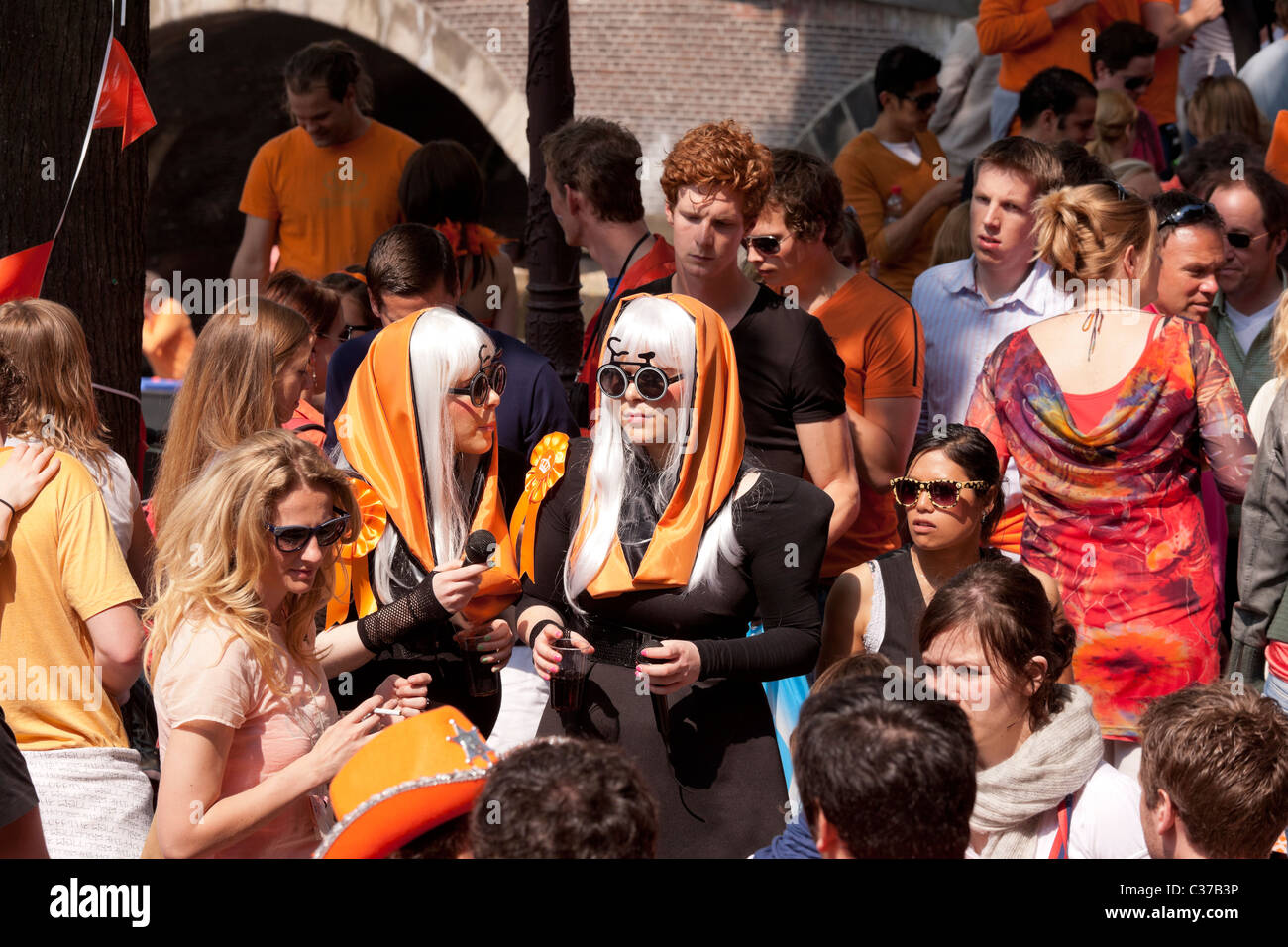 Zwei Lady Gaga Look-a-Likes am Königstag, der Geburtstag des Königs in Amsterdam. Lustige Hüte und Brillen und viel orange Gewand. Stockfoto