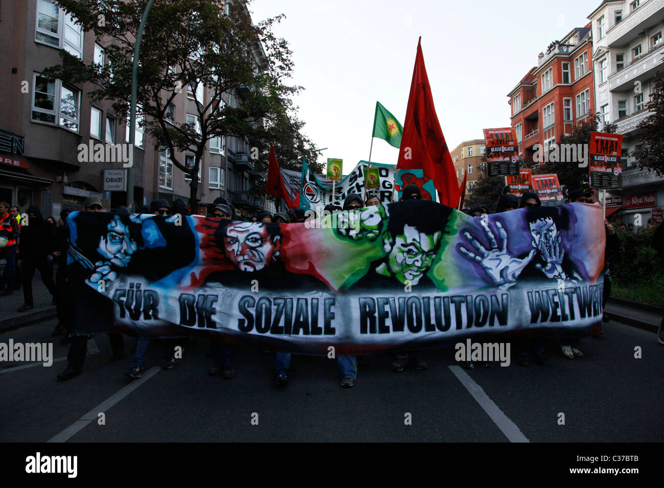 Linke und Antifa-Aktivisten halten ein Banner mit der Aufschrift "für die soziale Revolution weltweit", während sie während der Protestkundgebung am Internationalen Arbeitertag, auch bekannt als Labor Day oder May Day am 01. Mai im Berliner Bezirk Kreuzberg Deutschland, marschieren Stockfoto