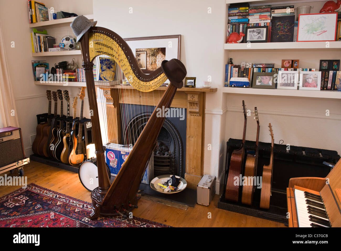 Musikzimmer mit Vintage-Konzertgitarren dreifache Harfe und Klavier im Haus des Musikers mit antiken Kamin Stockfoto