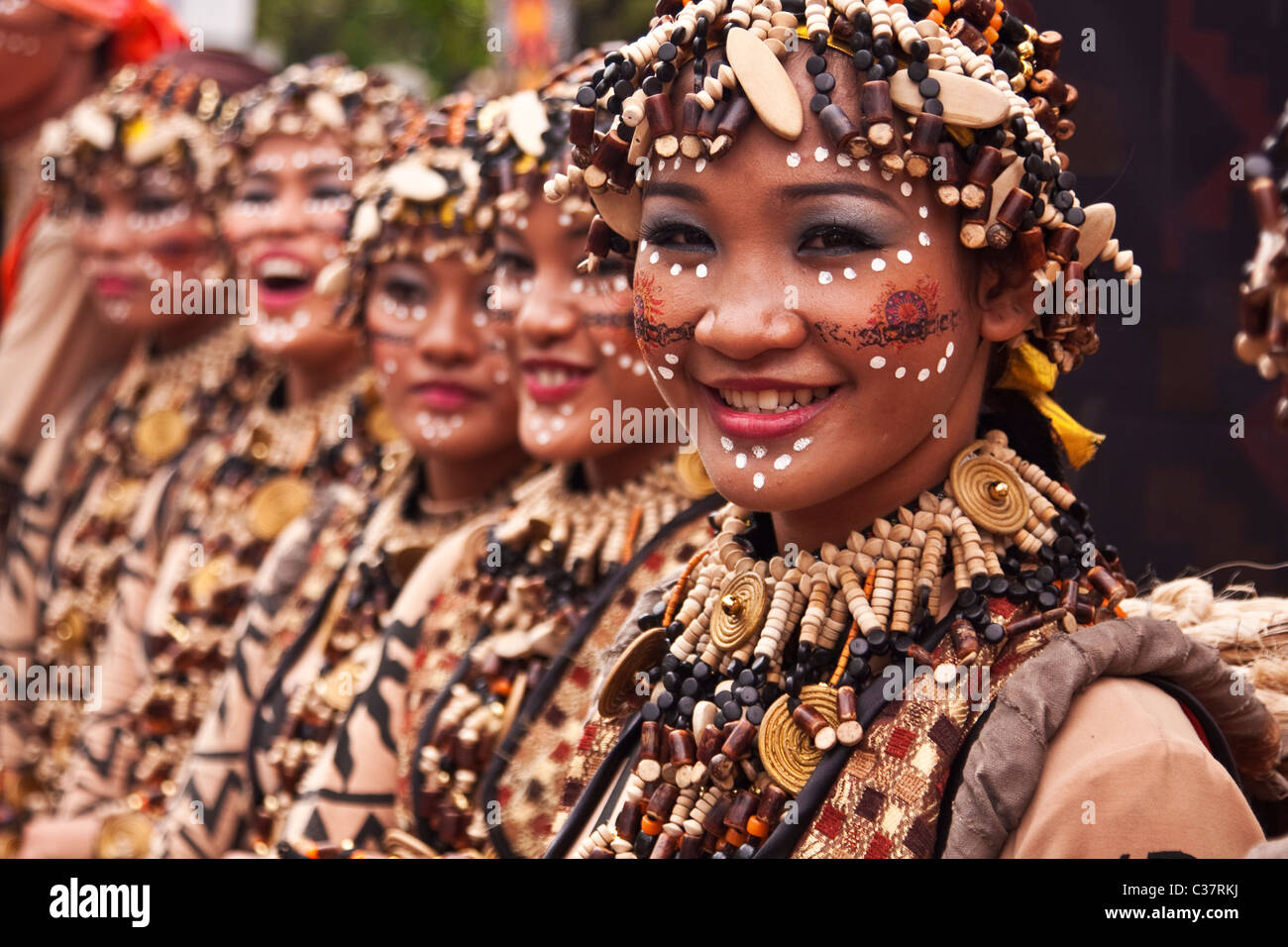 Lächelnde Frauen in Stammes-Kleidung gekleidet und bemalte Gesichter vorbereiten für den Streetdance-Wettbewerb Stockfoto