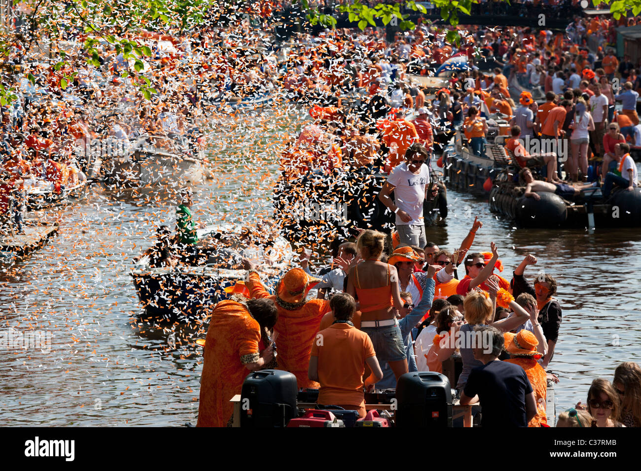 Königstag, des Königs Geburtstag (Königinnentag Königinnentag) in Amsterdam Canal Parade Boote Menschen feiern schießen orangefarbene Konfetti. Stockfoto
