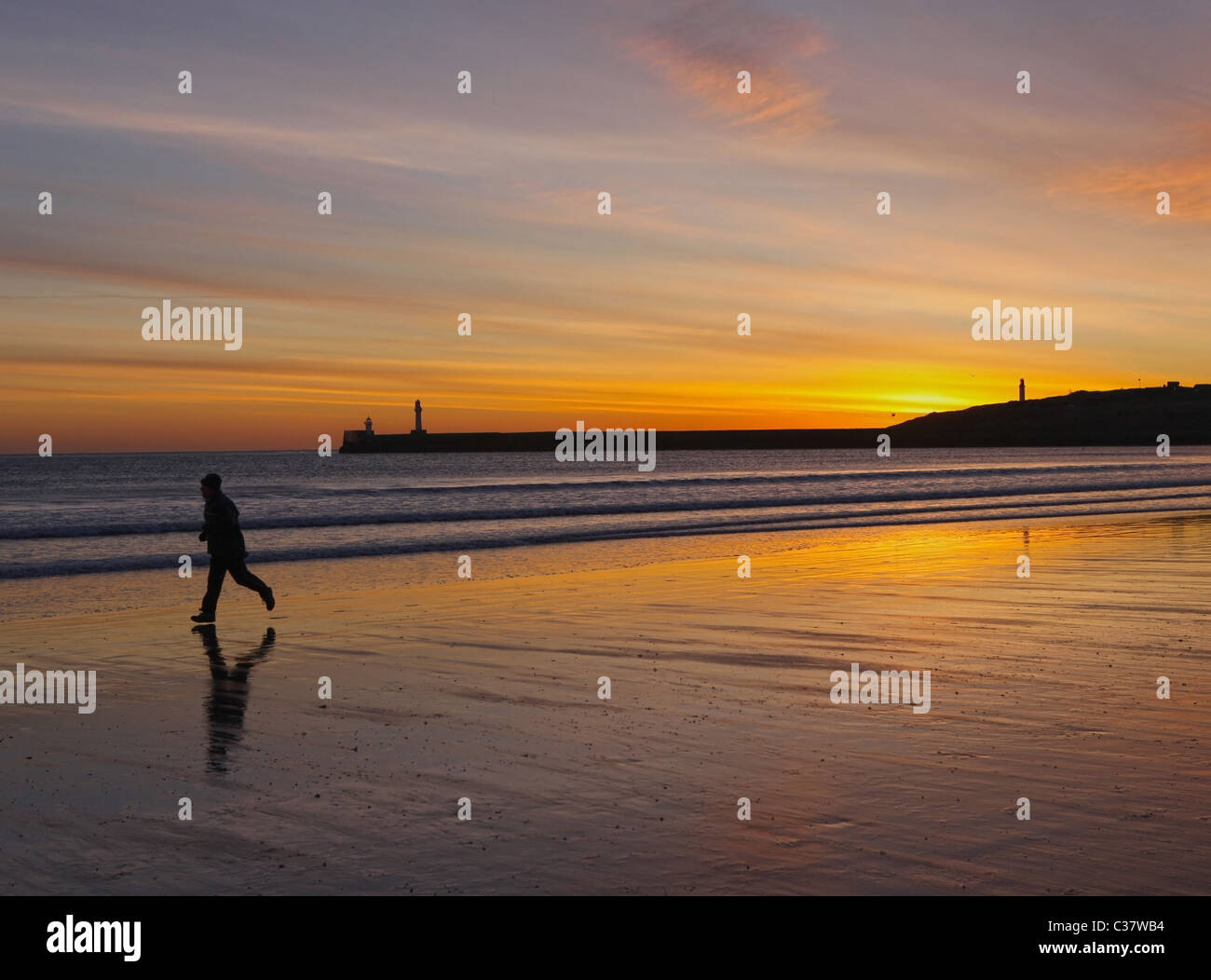 Ein einsamer Läufer am Strand bei Sonnenaufgang in Stadtzentrum von Aberdeen, Schottland, Großbritannien Stockfoto