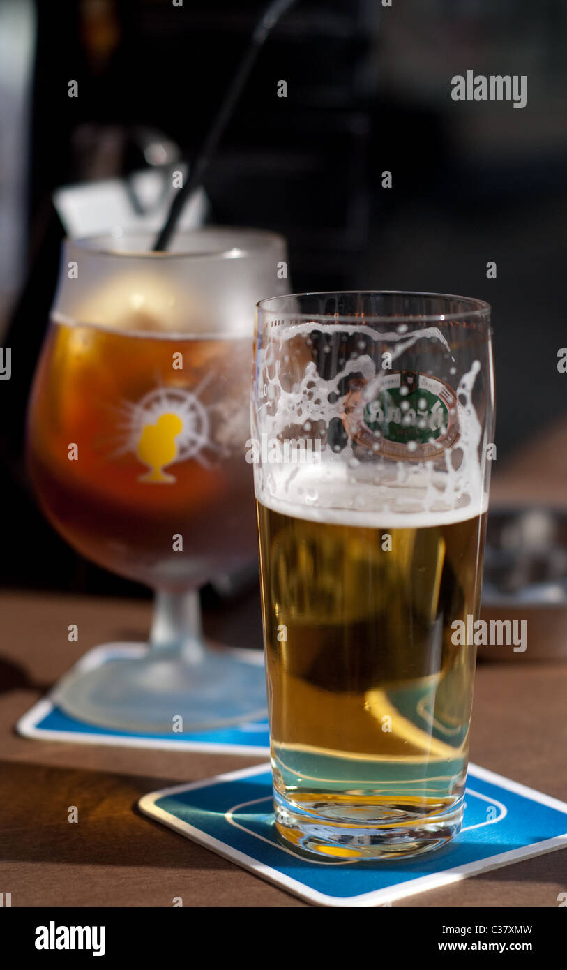 ein Glas Bier und ein Glas Eistee stehen auf Bierdeckeln auf eine Café-Tisch Stockfoto