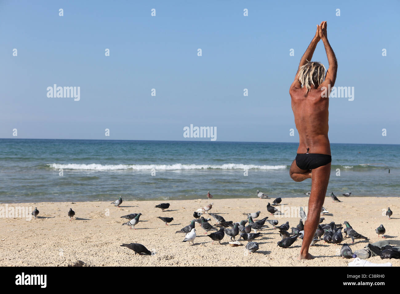 Mann tut Yoga am Strand Stockfoto