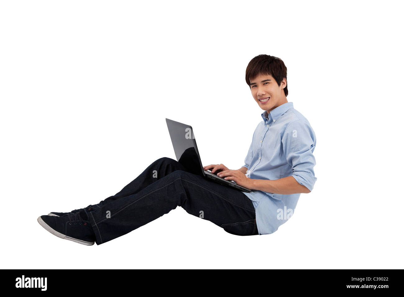 junger Mann mit Laptop auf dem Boden Stockfoto