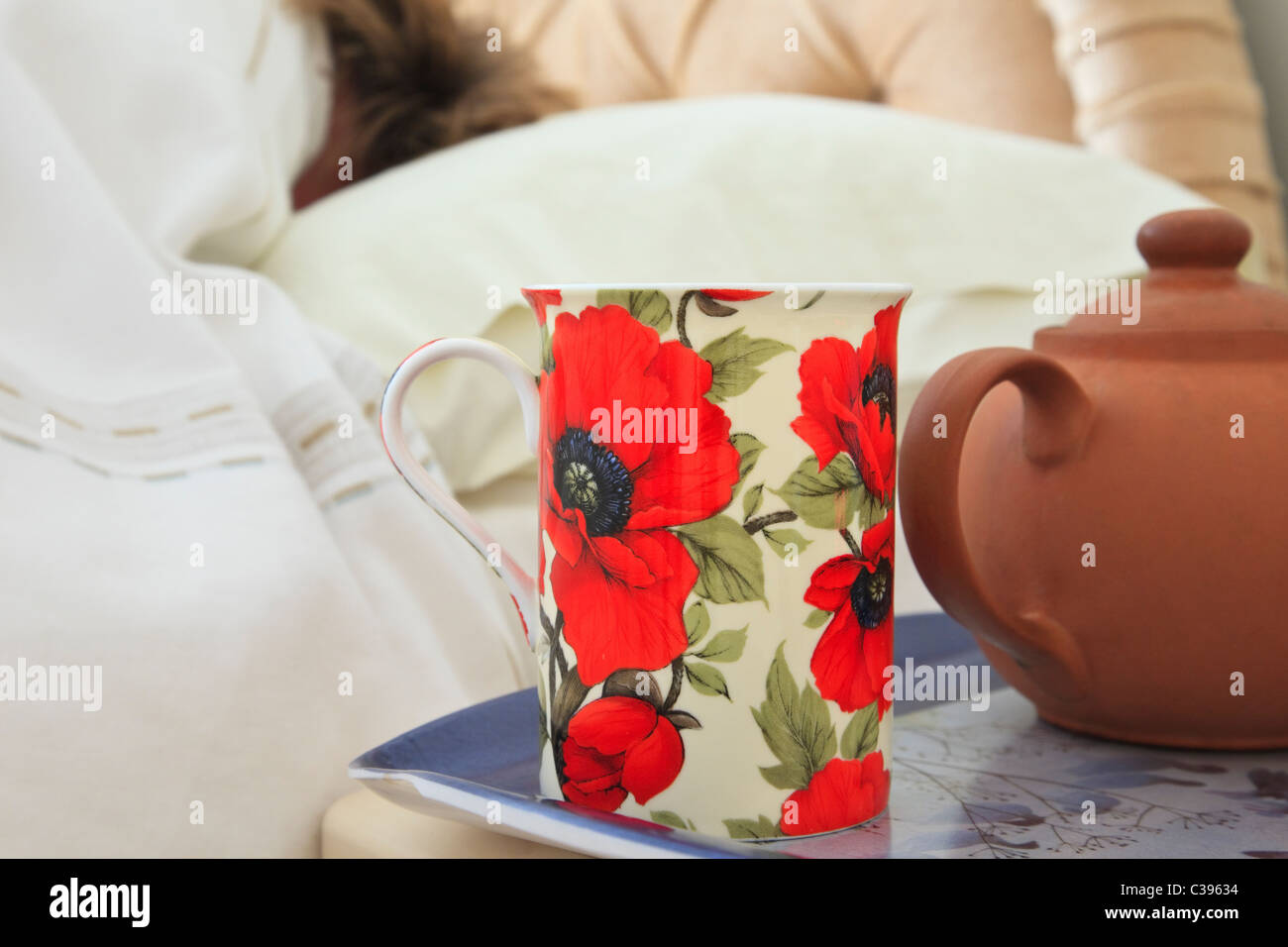 Alltäglichen Bild der eine Morgen Tasse Tee und Teekanne auf einem Nachttisch mit einer Person schlafen im Bett mit einer Bettdecke-Tag zu Hause. England-UK-Großbritannien Stockfoto
