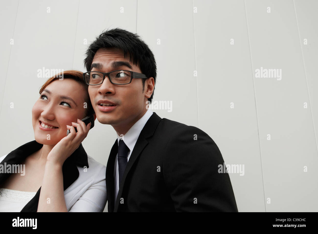 Zwei Personen auf der gleichen Handtelefon hören Stockfoto