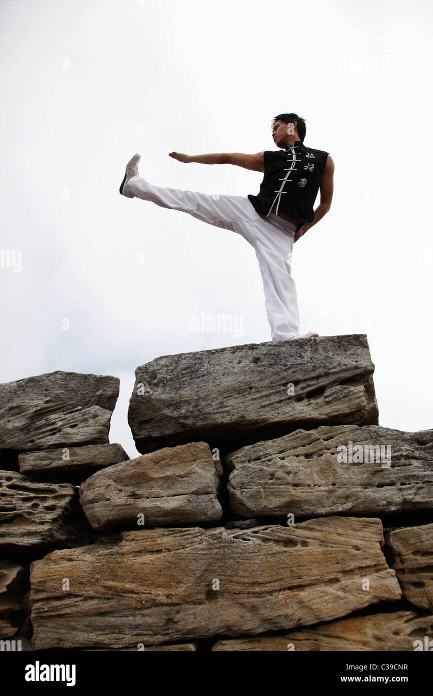 Chinesischer Mann tun Martial Arts auf große Felsen Stockfoto