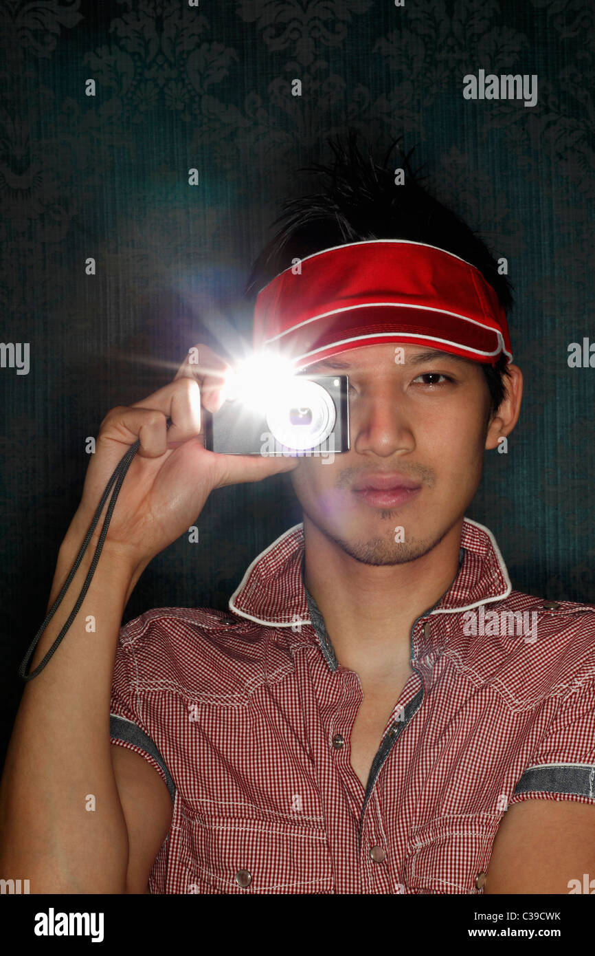 Junger Mann hält eine Kamera auf seinem Auge mit Blitz auf Stockfoto