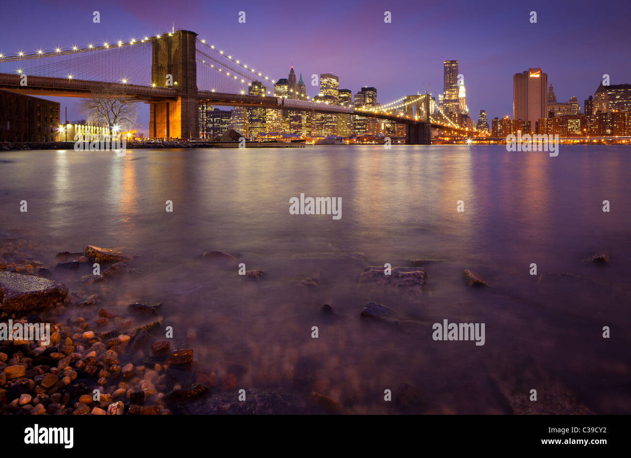 New Yorker Brooklyn Bridge, die den East River zwischen Manhattan und Brooklyn kreuzt, ist hier in der Nacht gesehen. Stockfoto
