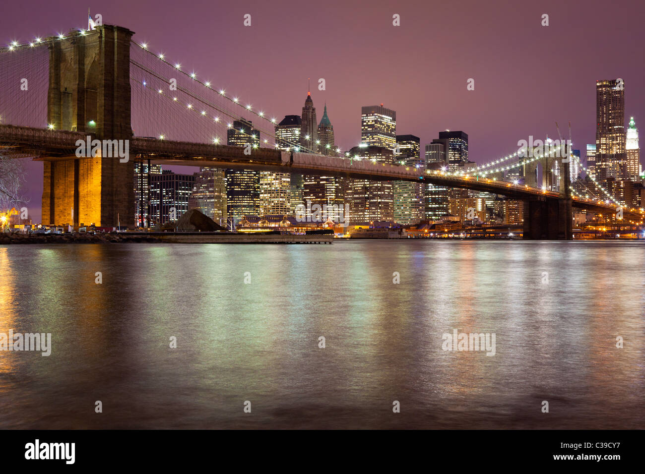 New Yorker Brooklyn Bridge, die den East River zwischen Manhattan und Brooklyn kreuzt, ist hier in der Nacht gesehen. Stockfoto