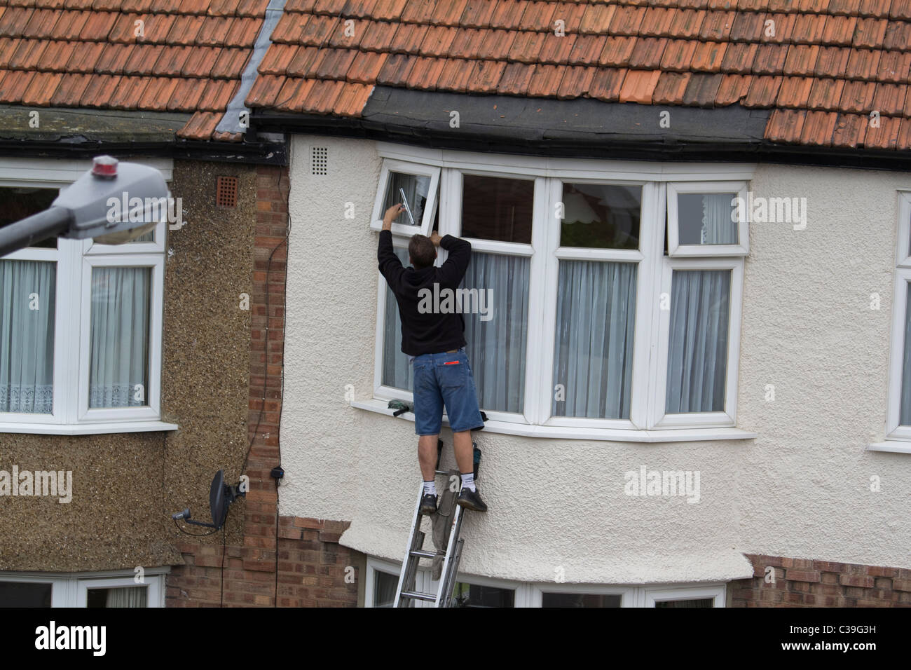 Fensterputzer arbeitet an Wohnhaus in London uk Stockfoto
