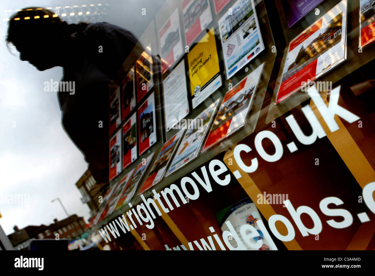 Ein rightmove.co.uk Schild am Fenster eines Immobilienmaklers in London mit einem Schatten einer Frau, Blick auf die Immobilien, die Stockfoto