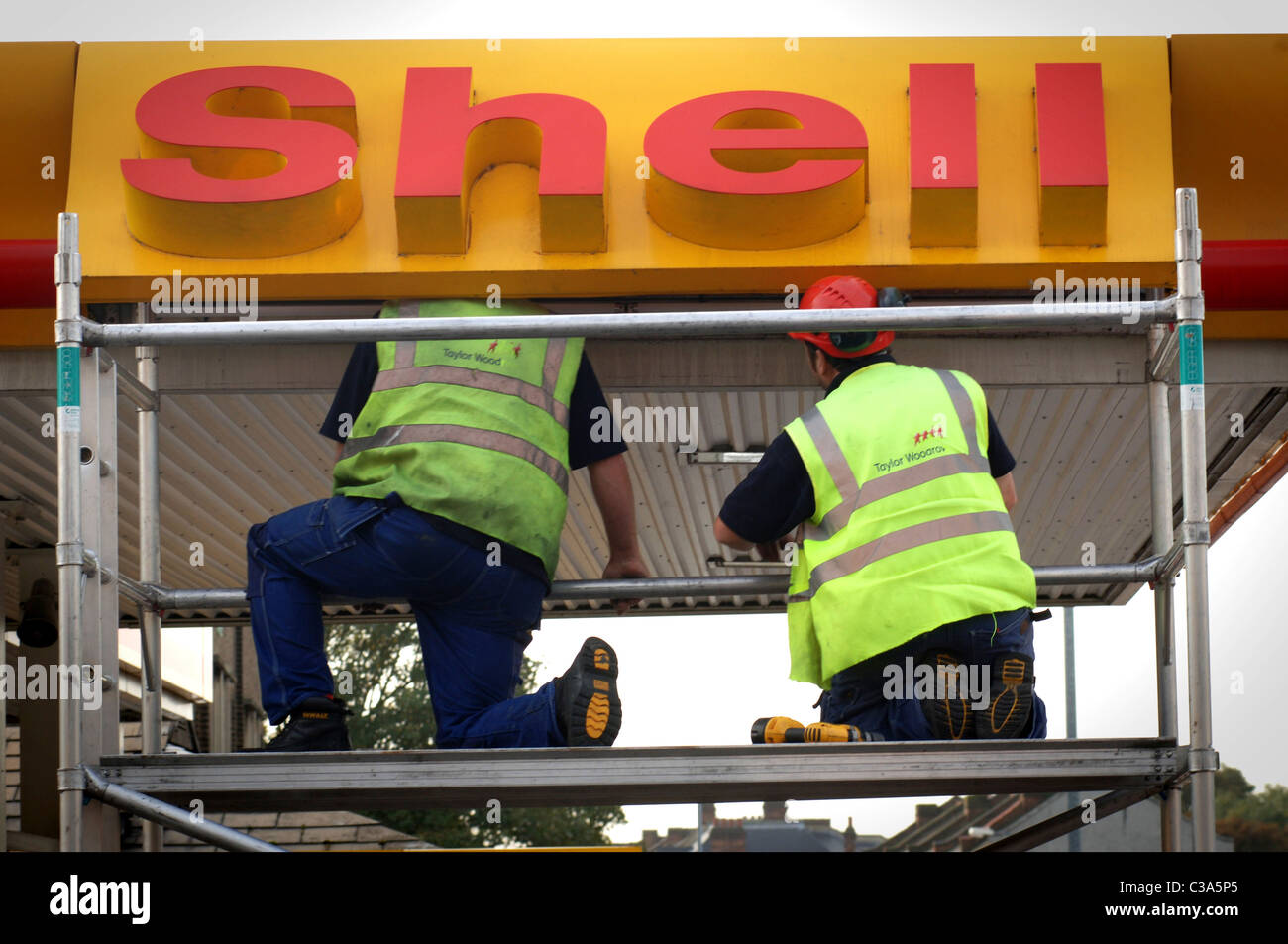 Männer, die um die Shell-Logo an einer Tankstelle in London zu reparieren Stockfoto