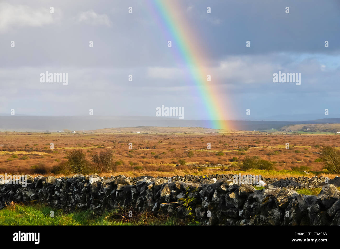 Regenbogen trifft die Erde in ein leeres Feld in County Clare, Irland. Stockfoto