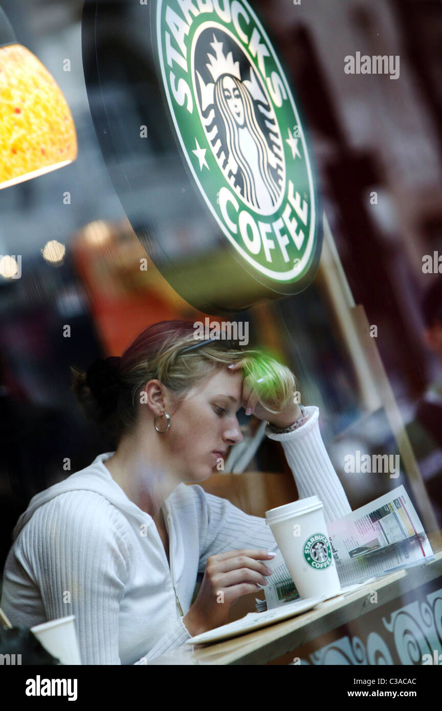 Bild zeigt eine Frau in einem Starbucks entspannend auf der Oxford Street, London. Stockfoto