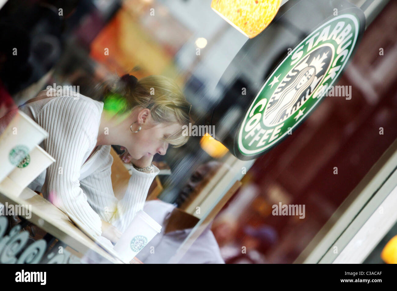 Bild zeigt eine Frau in einem Starbucks entspannend auf der Oxford Street, London. Stockfoto
