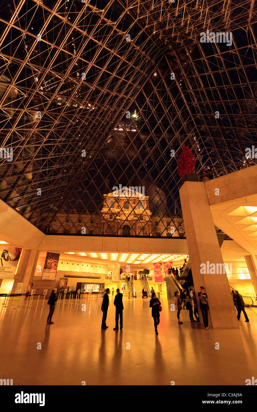 Der Louvre-Palast durch die Glaspyramide vom Concourse des Museums bei Nacht, Paris Stockfoto