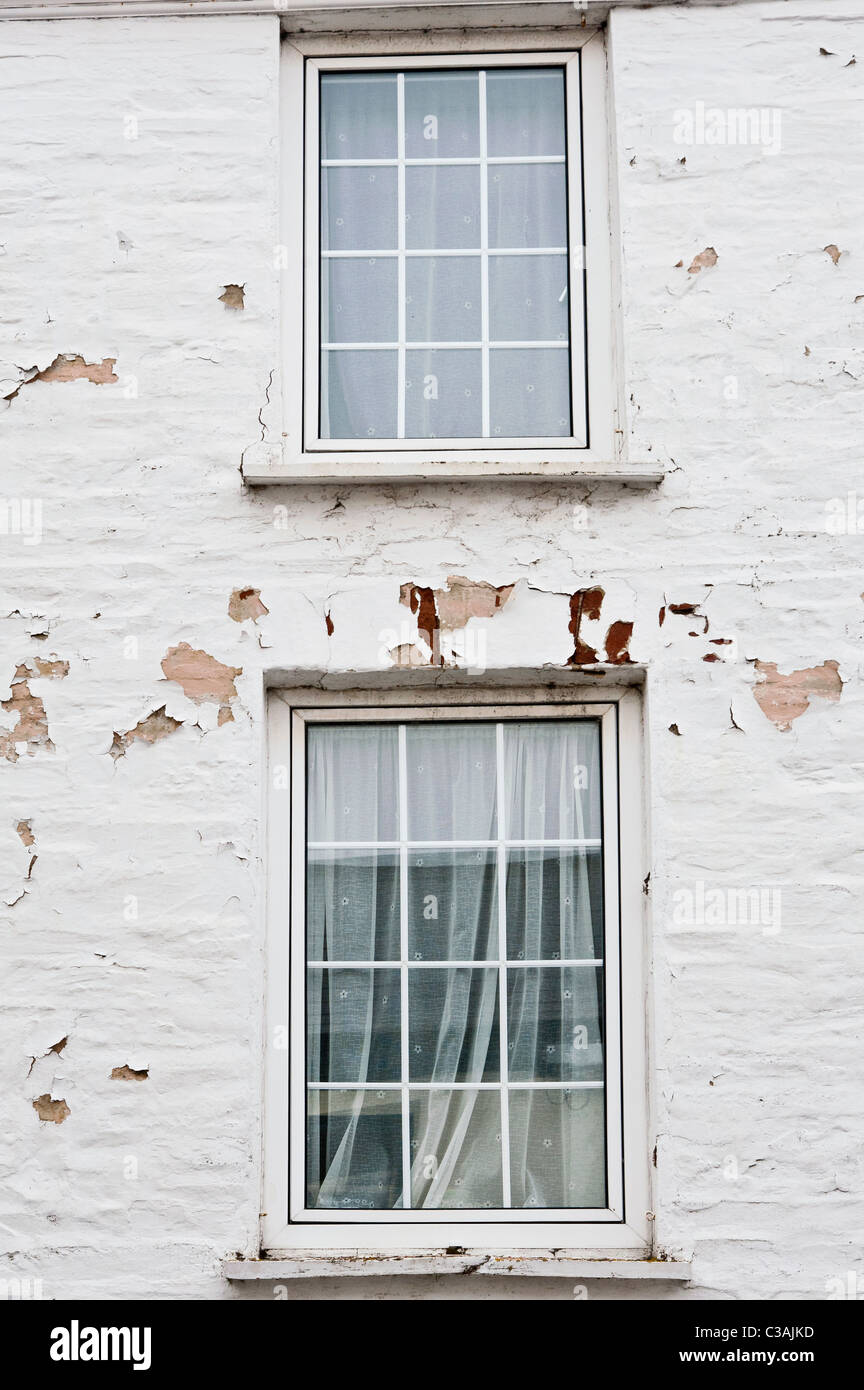 Zwei Fenster in eine weiß gestrichene Wand. Die Lackierung ist verfallen und blätterte von der Wand aufgrund der Exposition gegenüber am Meer Wetter. Stockfoto