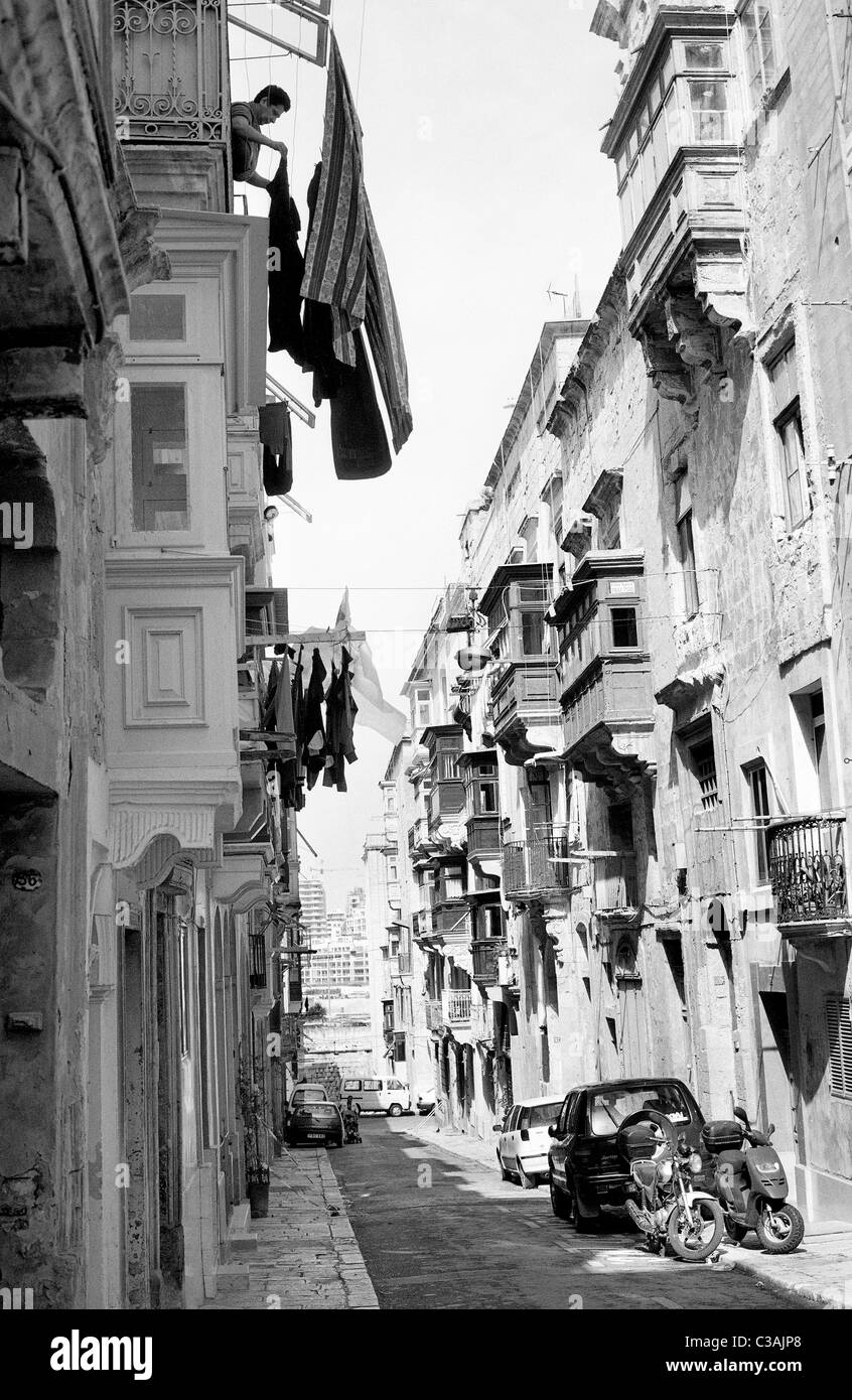 Frau, hängen die Wäsche zum Trocknen auf ihren Holzbalkon am Hospital Street in der maltesischen Hauptstadt Valletta. Stockfoto