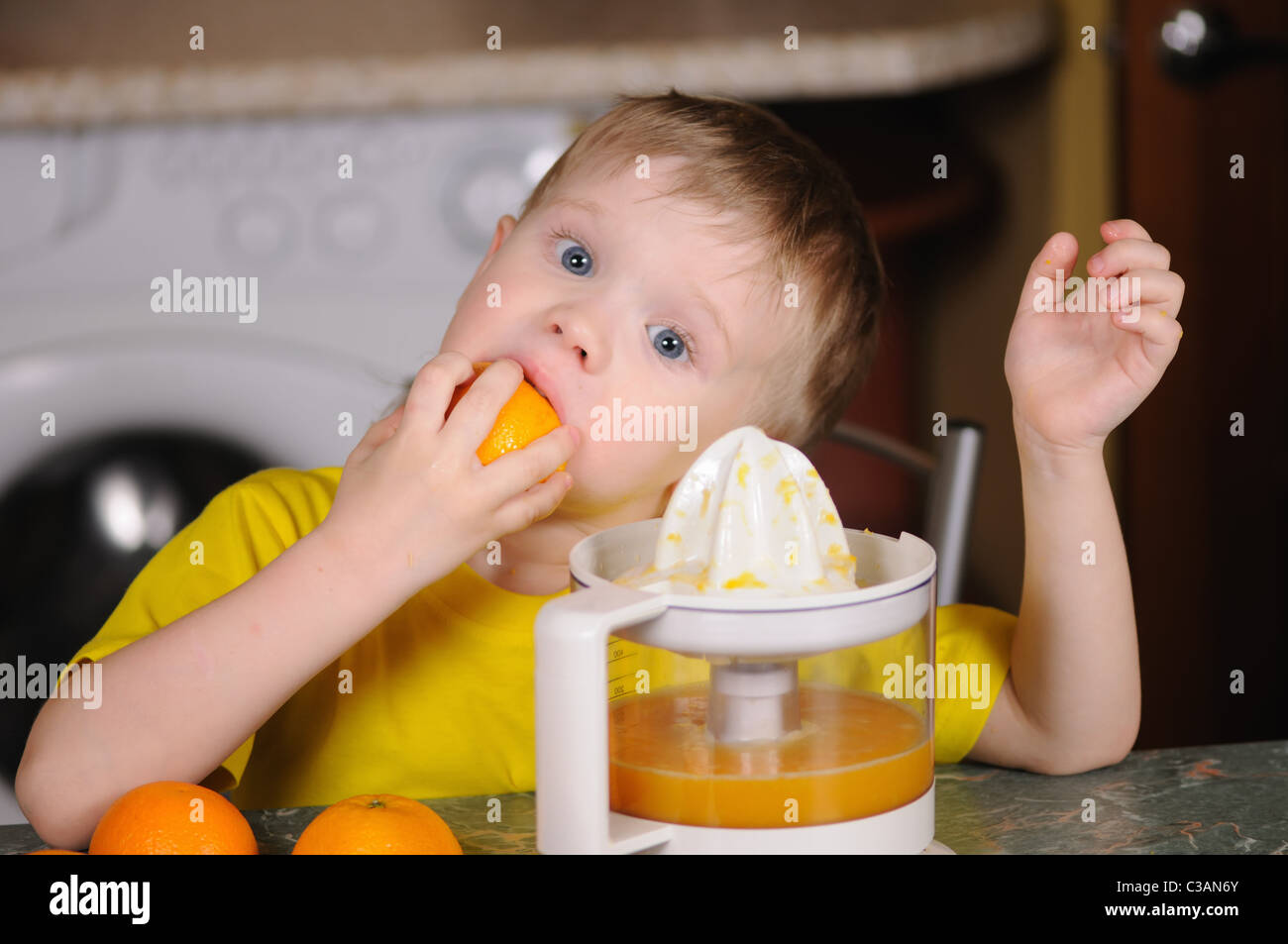 Das Kind in eine gelbe Weste, auswringen, Saft von einer orange Stockfoto